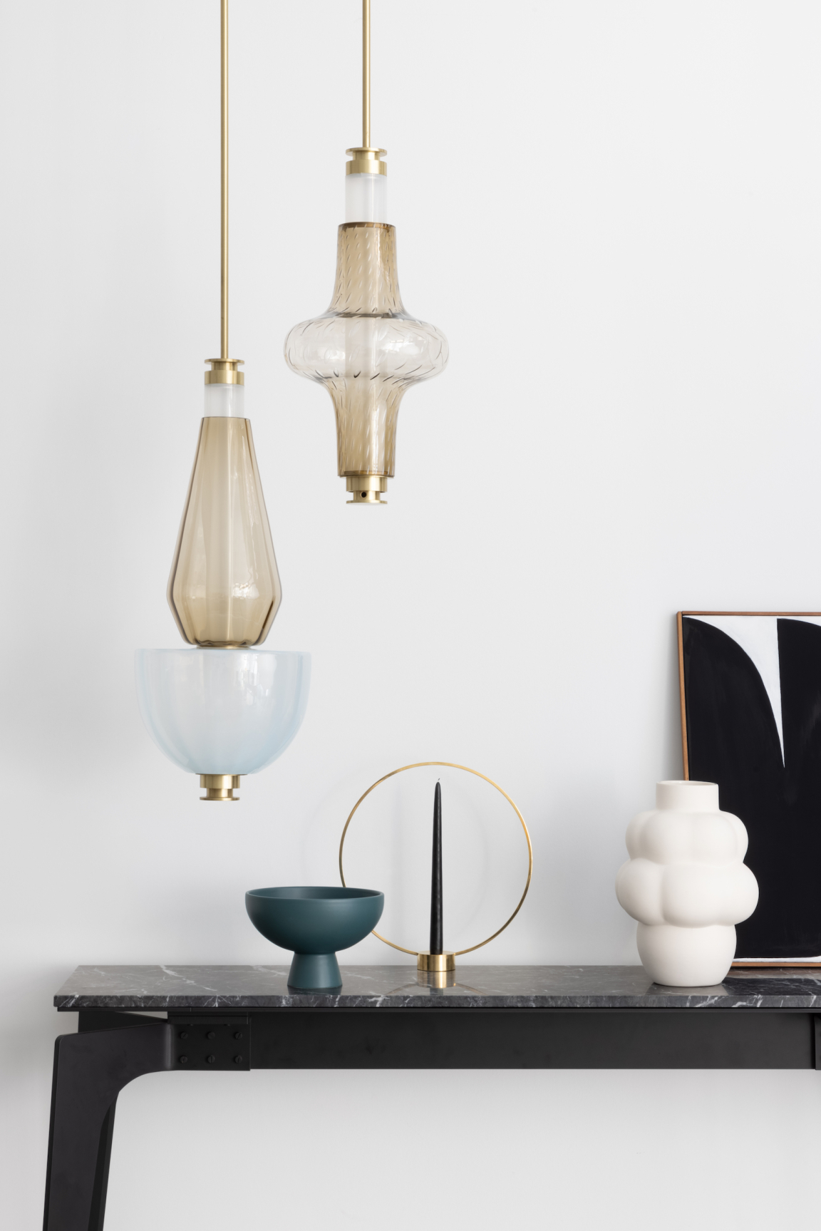 Luna Kaleido collection pendant lights displayed on a modern black table alongside decorative vases and sculptural objects.
