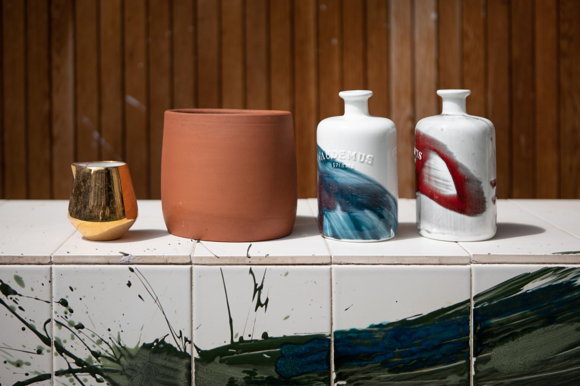 Ceramic vases and terracotta pots arranged on a tiled surface, showcasing Reiko Kaneko's unique design style.