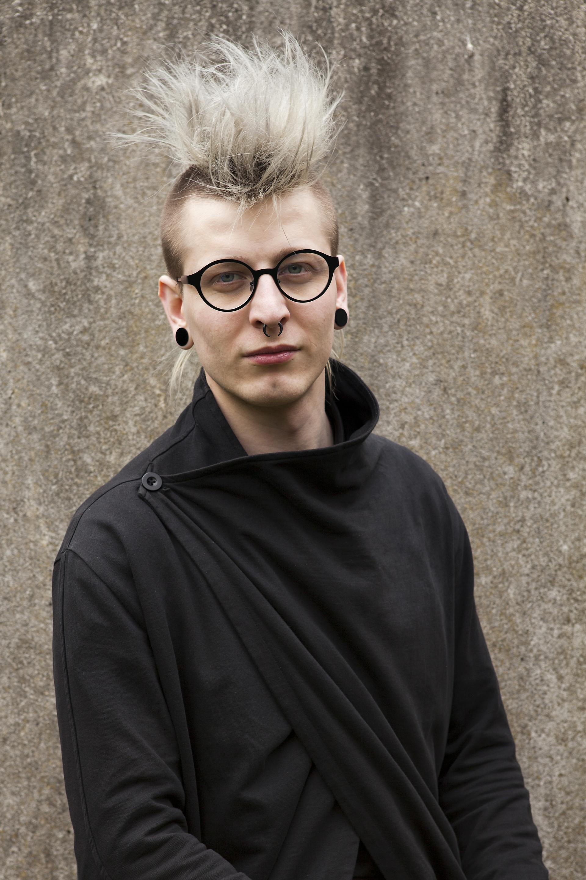 Atticus Durnell poses in a black outfit, showcasing the innovative sustainable design of That’s Caffeine products.