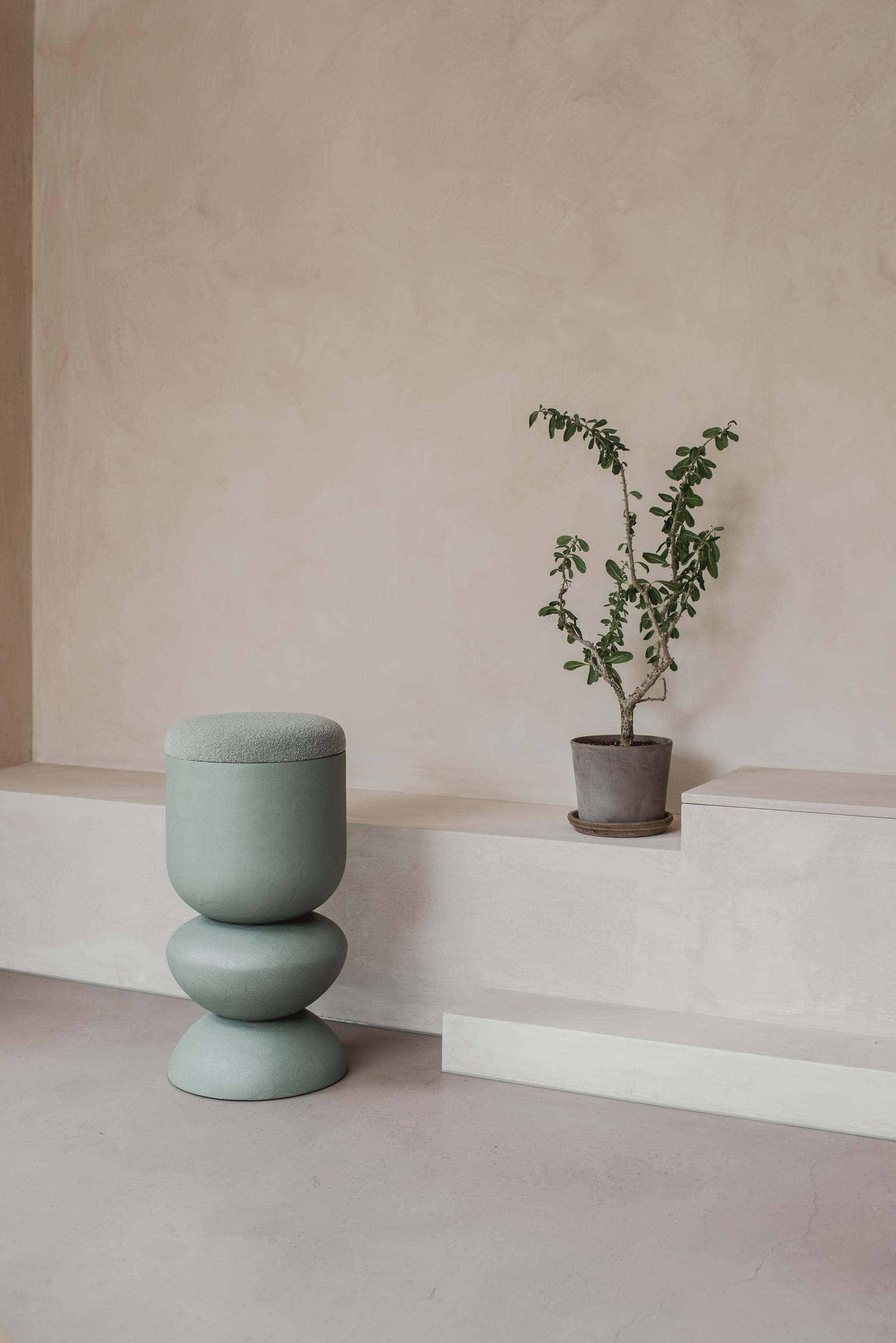 Curvaceous mint-green stool alongside a potted plant, showcasing Sella Concept's new furniture collection inspired by Hampstead Ladies’ Pond.