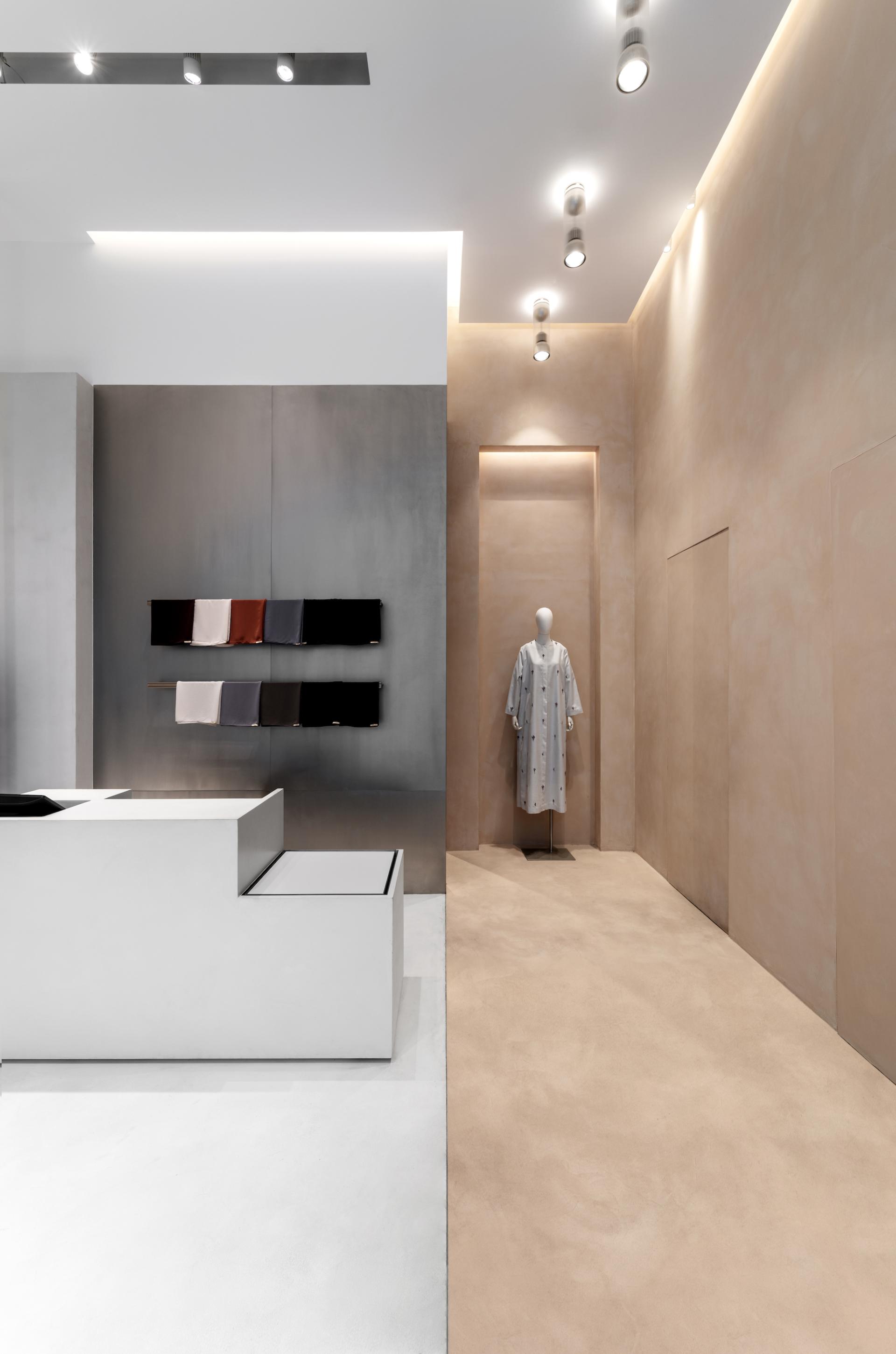 Minimalist boutique interior featuring modest women's fashion garments displayed elegantly against sleek, modern walls.