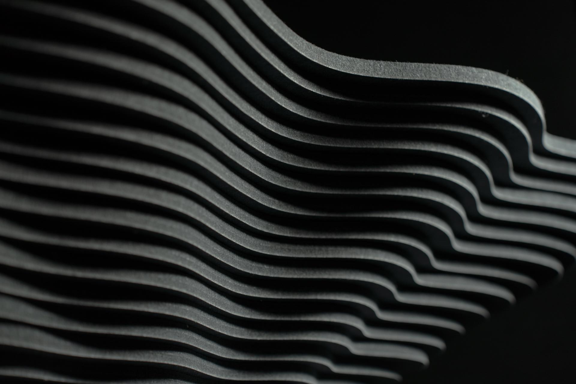 Wavy textured black acoustic panels inspired by natural landscapes, showcasing Autex's innovative new colors.