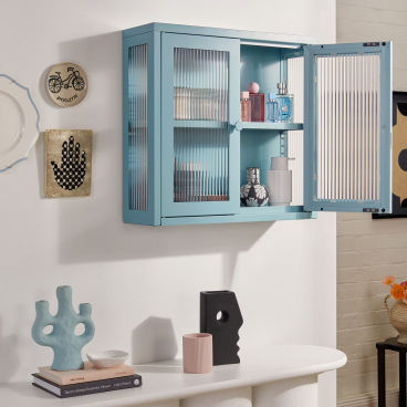 Stylish light blue cabinet showcasing The Glass Collection with decorative items on a white console table.