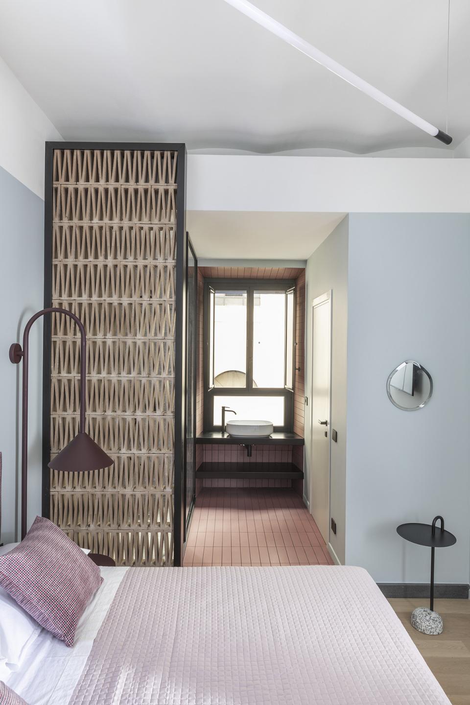 Stylish bedroom interior featuring a modern design, a wooden partition, and an elegant view into the bathroom area.