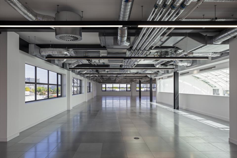Spacious office interior featuring exposed ductwork, large windows, and modern architectural design by Material Works Architecture.