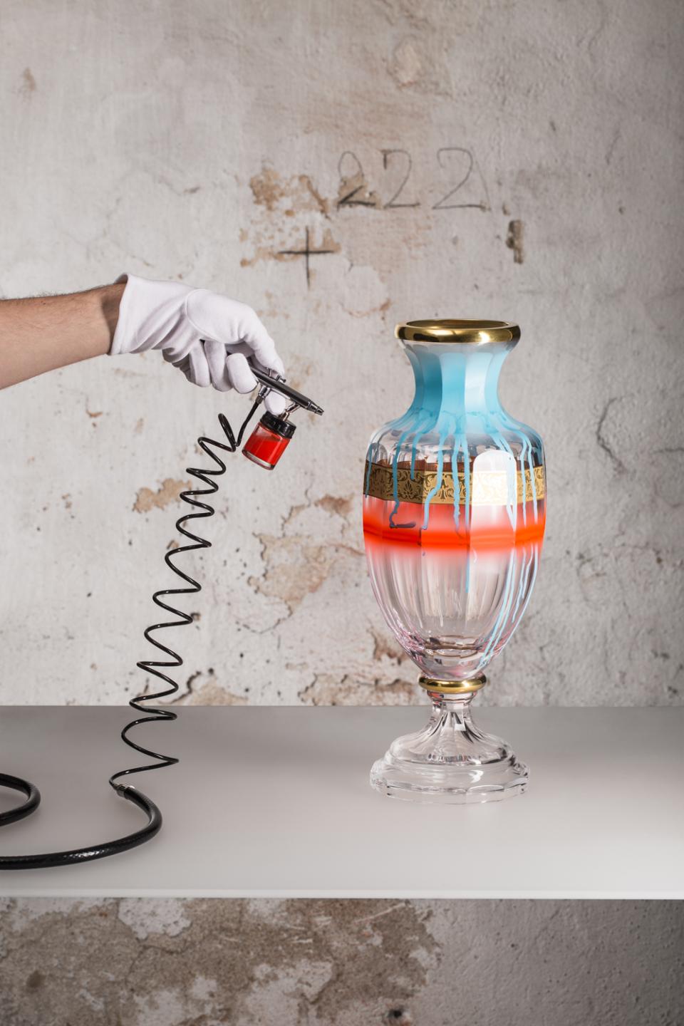 Artist applying vibrant colors to a decorative glass vase, showcasing innovative glass art techniques at the London Design Fair.