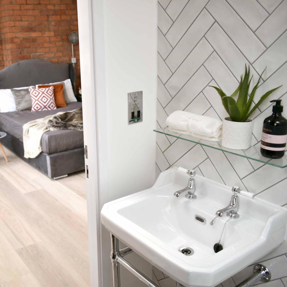 Stylish bathroom featuring a chic sink, modern decor, and a cozy bedroom in the background of Gramercy House apartments.