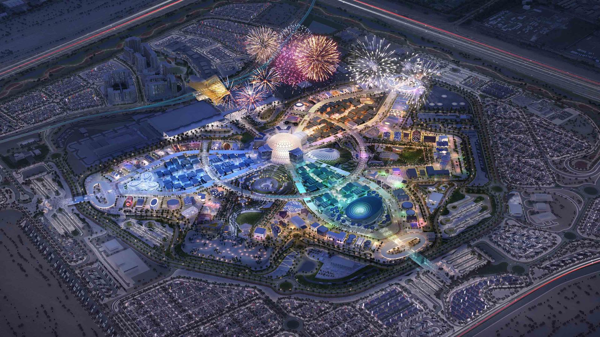Aerial view of a vibrant urban development in Dubai featuring fireworks, parks, and modern architecture for indoor and outdoor living.
