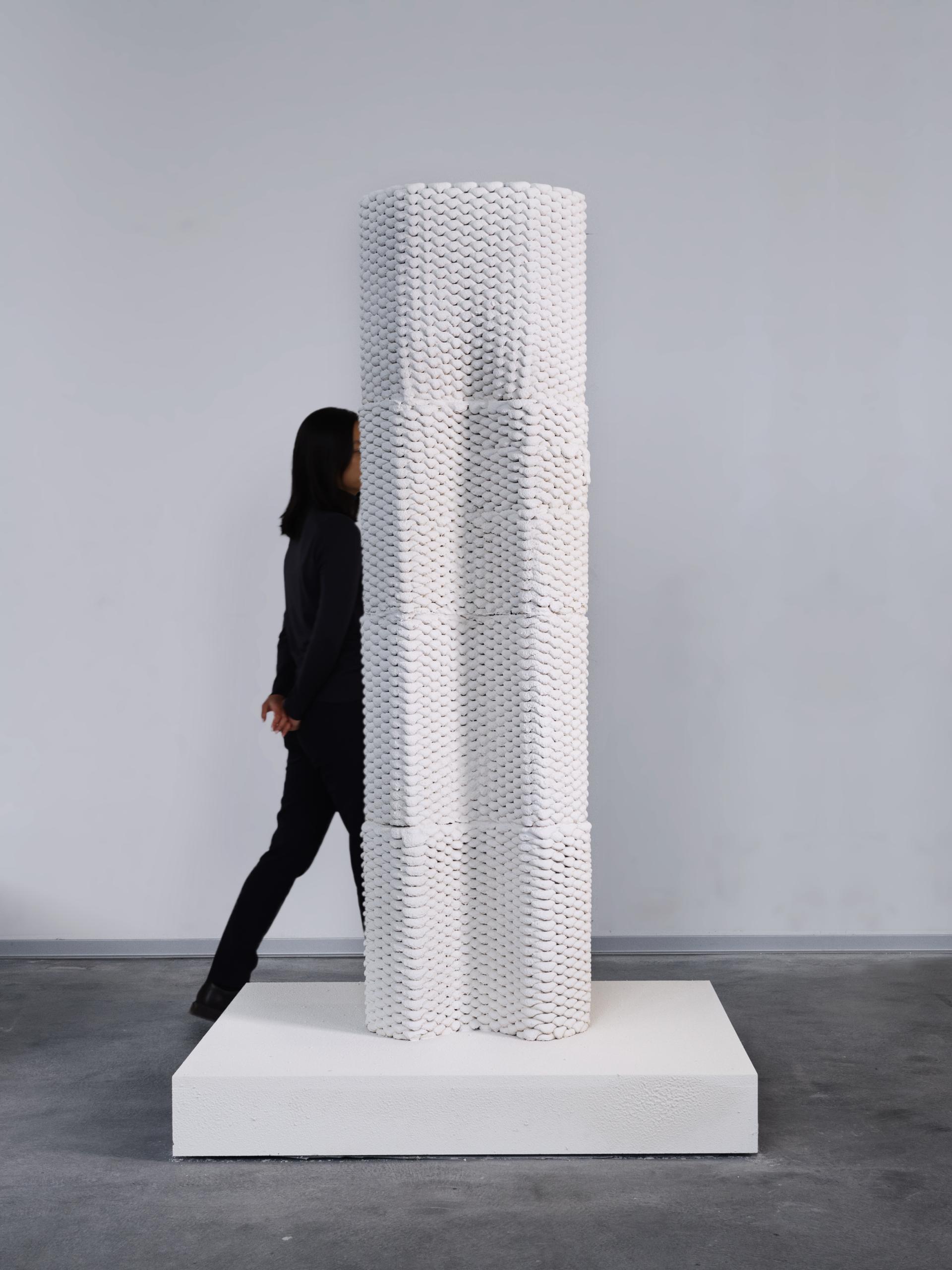 Innovative 3D printed white structure towering beside a person, showcasing advancements in construction technology for 2024.