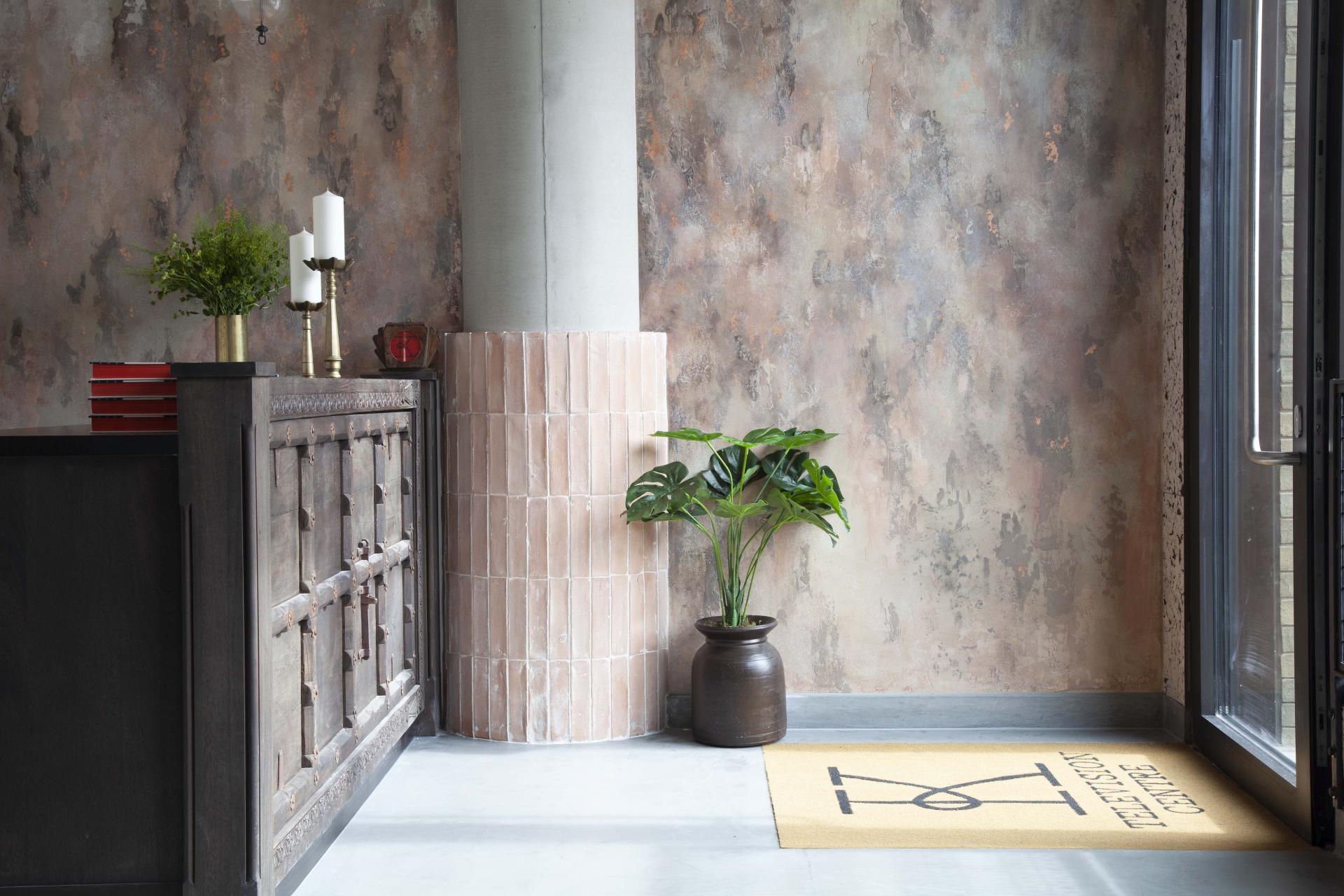 Stylish restaurant entrance featuring a wooden reception, plants, and textured walls at Kricket, Television Centre.