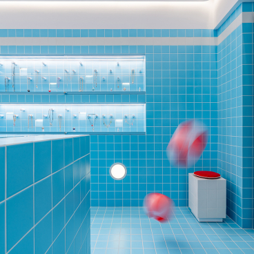 Bright blue-tiled jewellery shop interior inspired by Wes Anderson, featuring elegant displays and playful red objects.