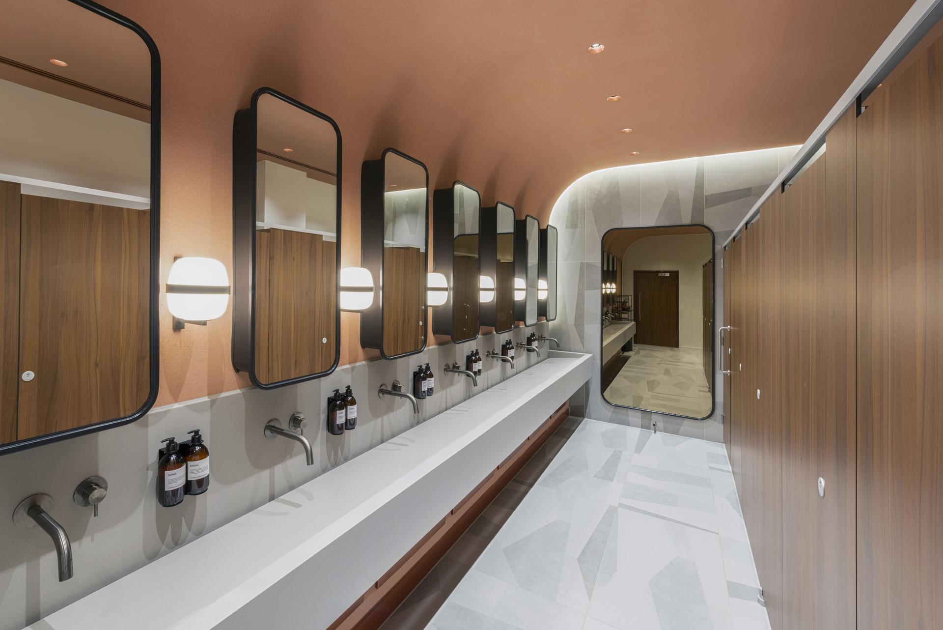 Sleek, modern restroom design featuring elegant lighting, mirrors, and minimalist fixtures by Taner's Sons Design Studio.