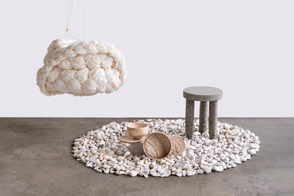 Textured stone setting featuring a unique hanging light, minimalist table, and handcrafted bowls in an innovative design display.