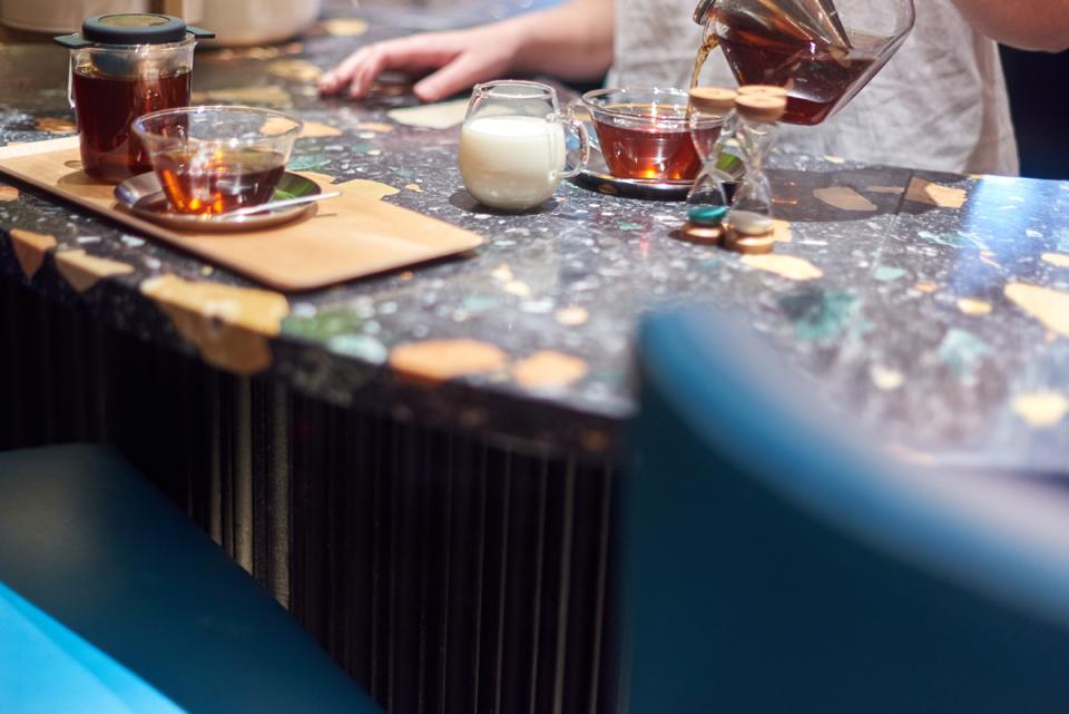 Elegant tea setup on a stylish art deco countertop, featuring tea, milk, and a decorated hourglass.