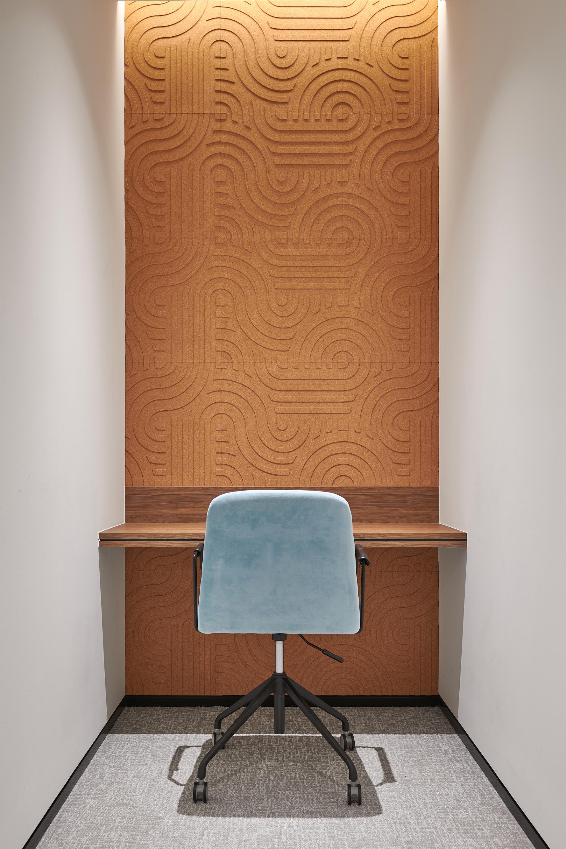 Modern workspace featuring a textured wall, stylish desk, and comfortable chair designed for the Sharjah Entrepreneurship Center.