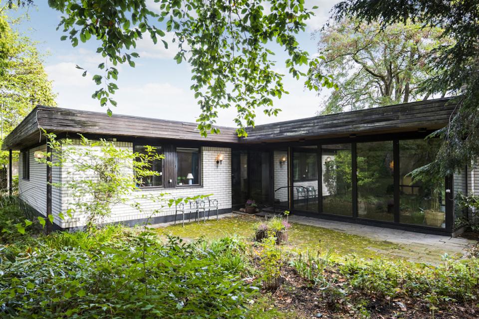 Scandinavian-style home with large windows, surrounded by greenery, showcasing functional architecture and design.