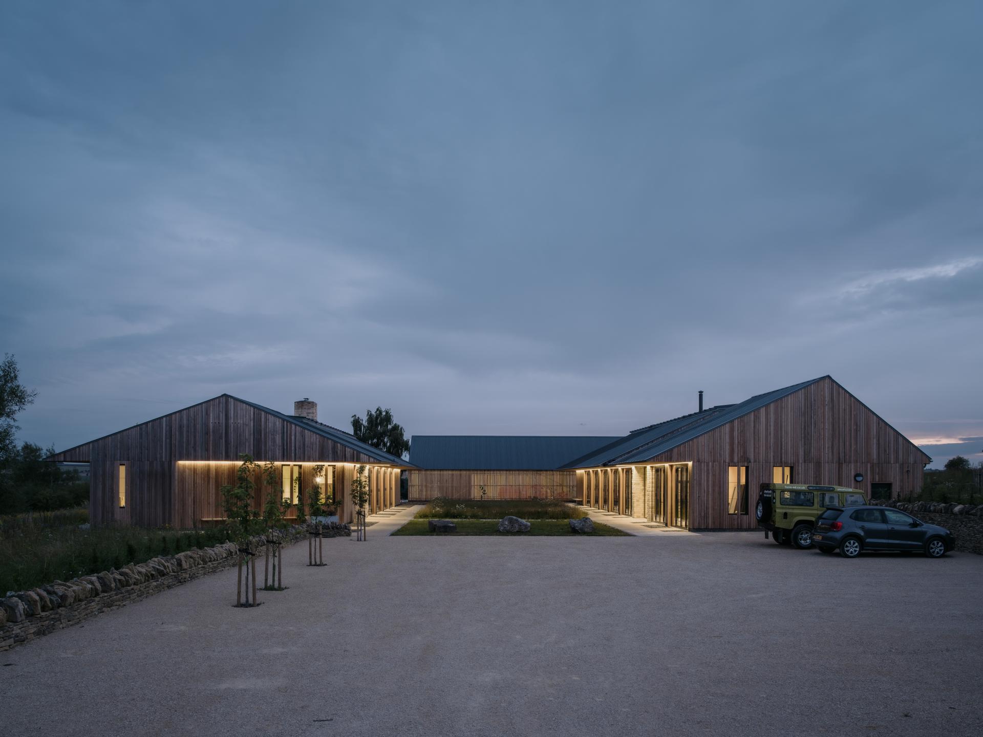 Sustainable farming education center in the Cotswolds, showcasing modern architectural design and landscaping at dusk.