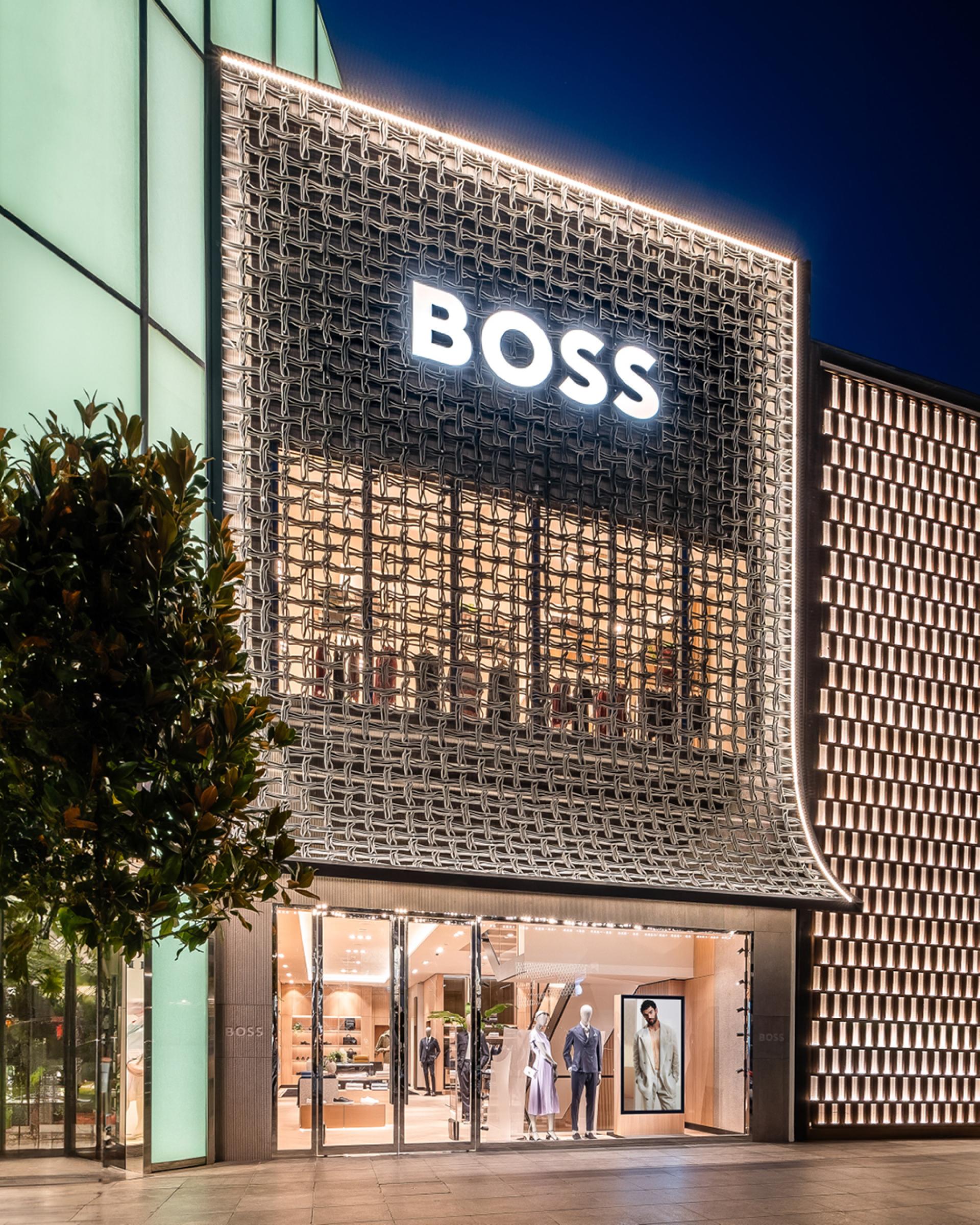 BOSS store in İstinye Park features an interlocking 3D printed façade crafted from recycled materials, illuminated at night.