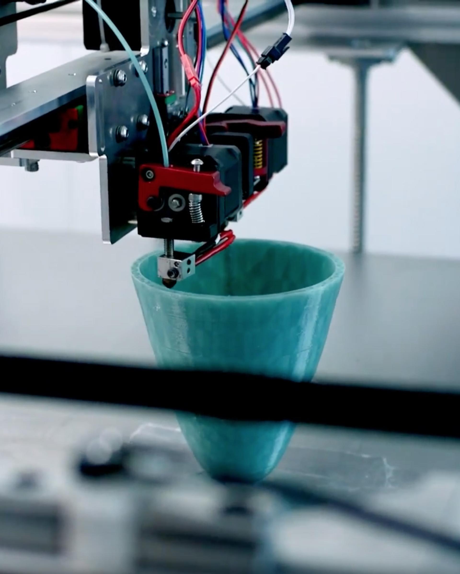 3D printer creating a turquoise vase from sustainable materials, highlighting the fusion of technology and local craftsmanship.