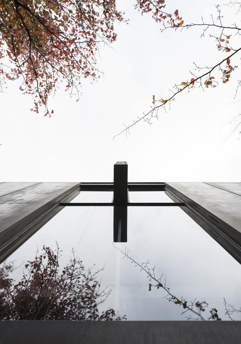 View from below of St Catherine’s College’s modern architecture reflecting autumn leaves and a cloudy sky.