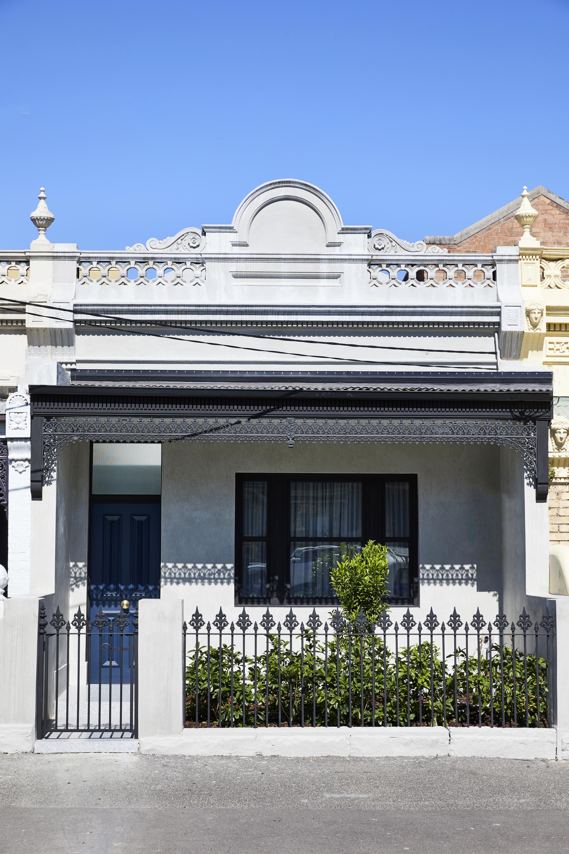 Melbourne family home featuring a renovated, Parisian-inspired facade with decorative ironwork and a vibrant blue door.