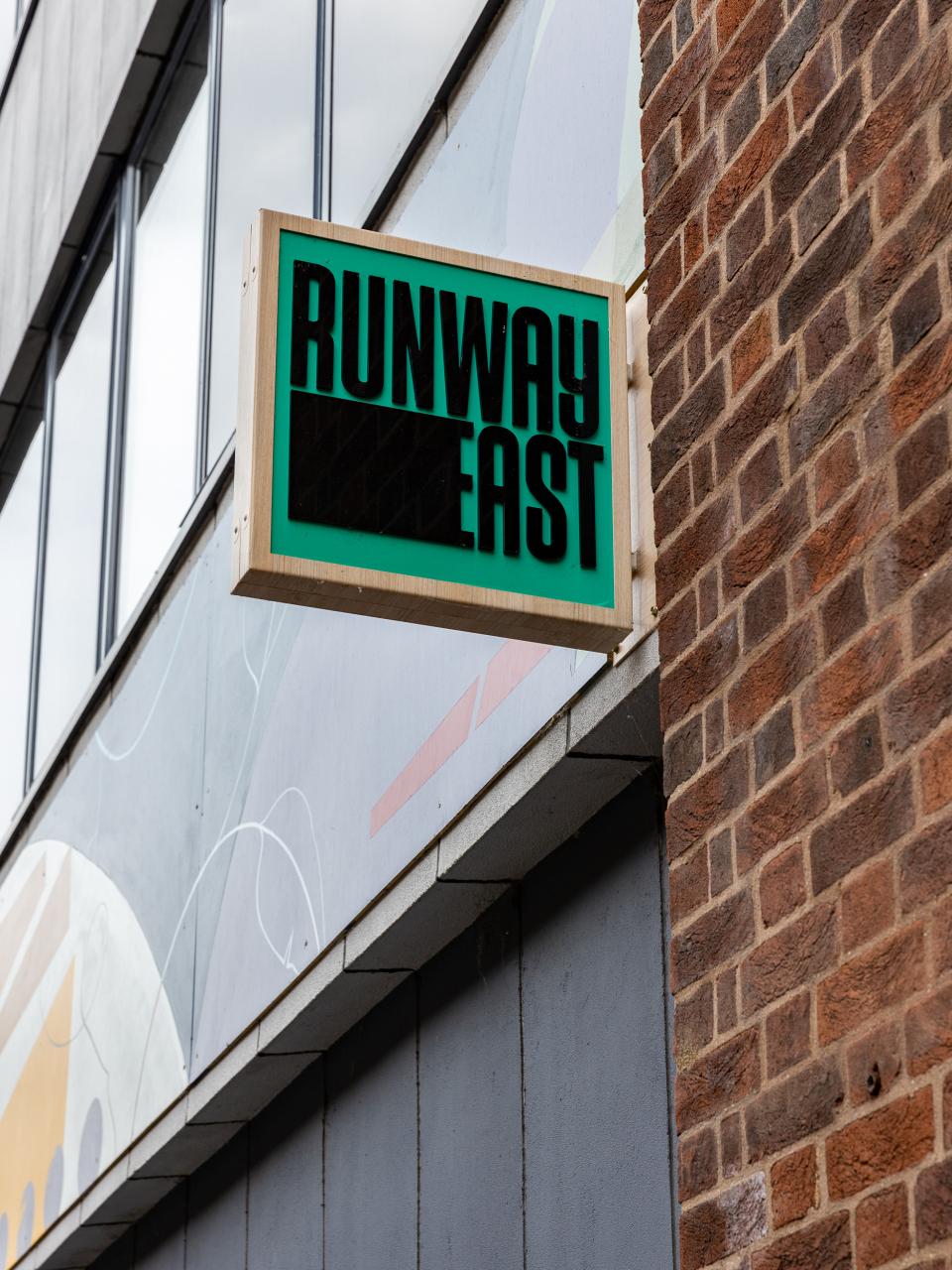 Runway East sign displayed on a building with vibrant patterns, showcasing creative workspace collaboration with Sheila Bird Studio.