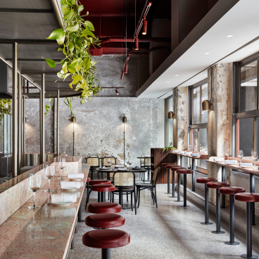 Stylish interior design of Pentolina, a Melbourne Italian restaurant, featuring marble countertops, bar seating, and greenery.