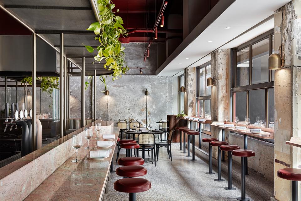 Stylish interior design of Pentolina, a Melbourne Italian restaurant, featuring marble countertops, bar seating, and greenery.