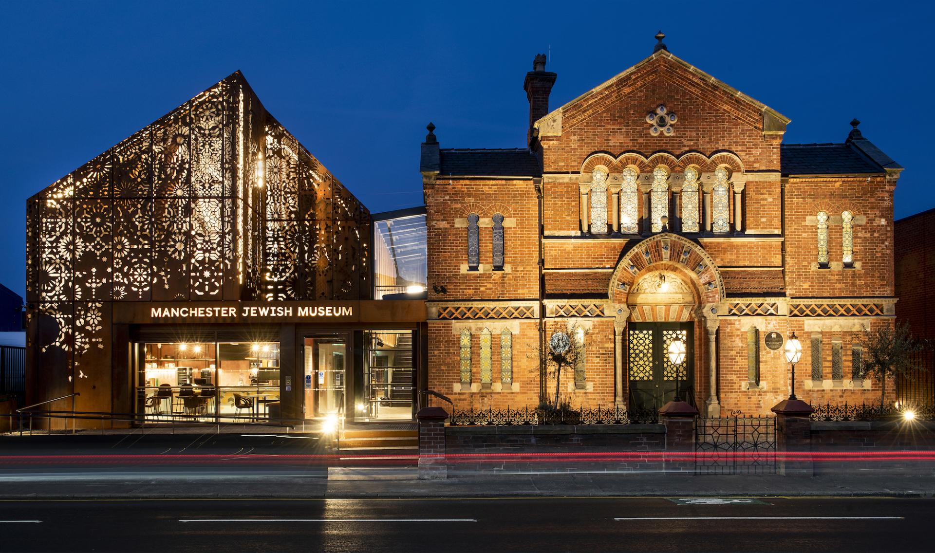 Manchester Jewish Museum features a striking blend of industrial corten steel and historic red brick architecture at twilight.