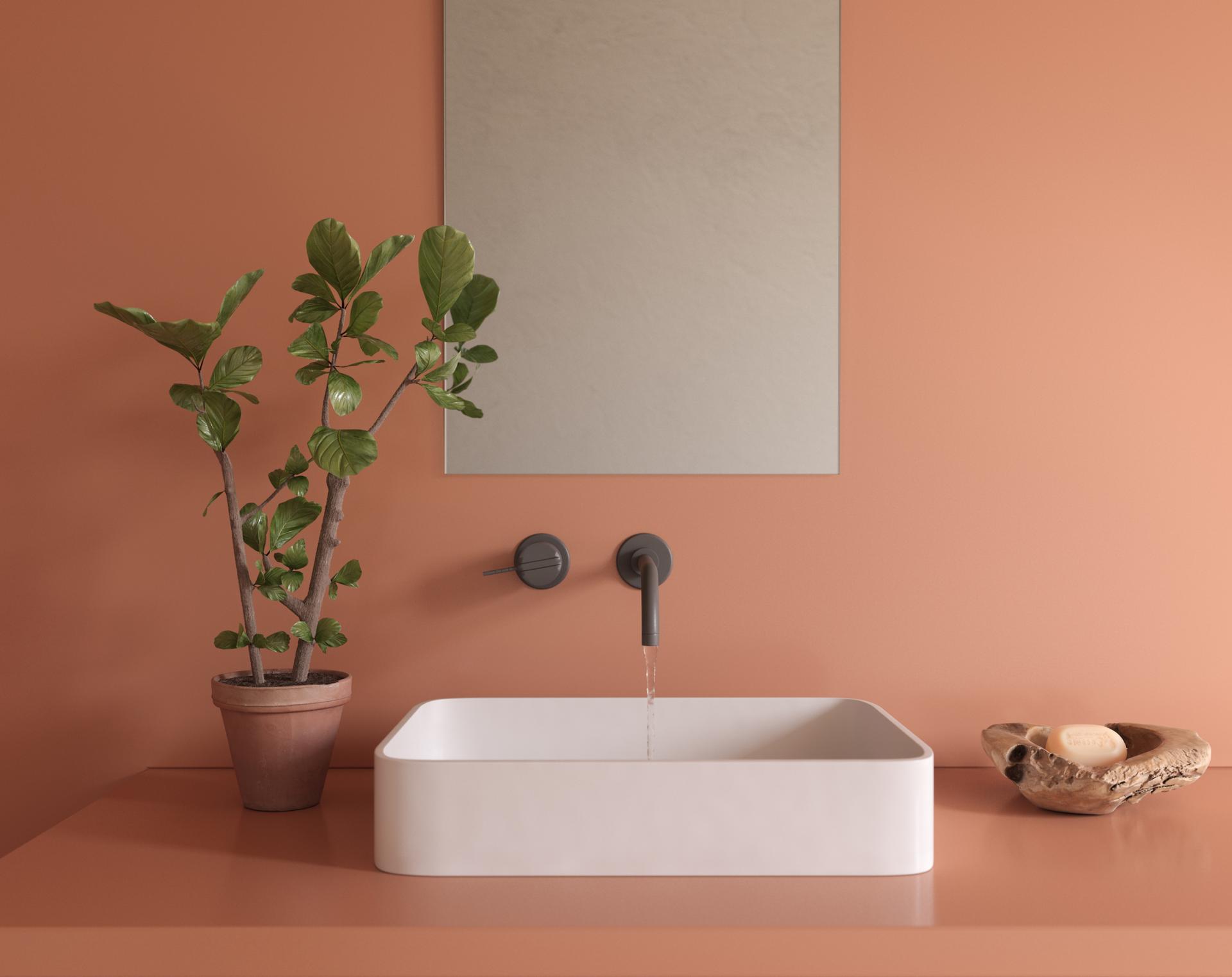Modern bathroom design featuring a sleek white sink, greenery, and soft terracotta walls for a stylish aesthetic.