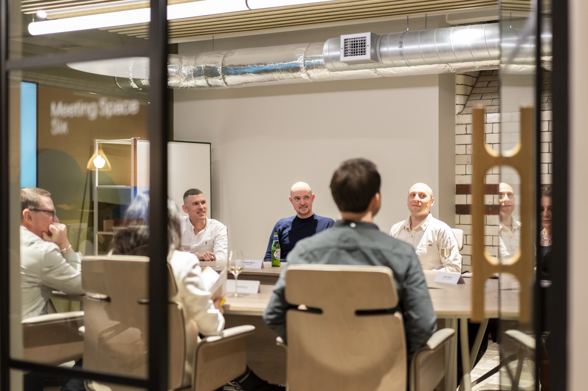 Group discussion on technology and sustainability in design, featuring professionals in a modern meeting space.