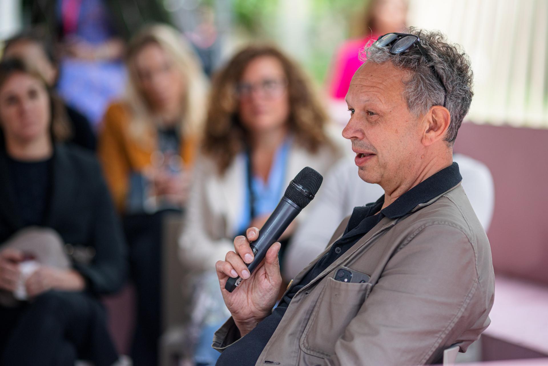 Tom Dixon speaks with a microphone, discussing biomaterials and the metaverse at a WGSN event.