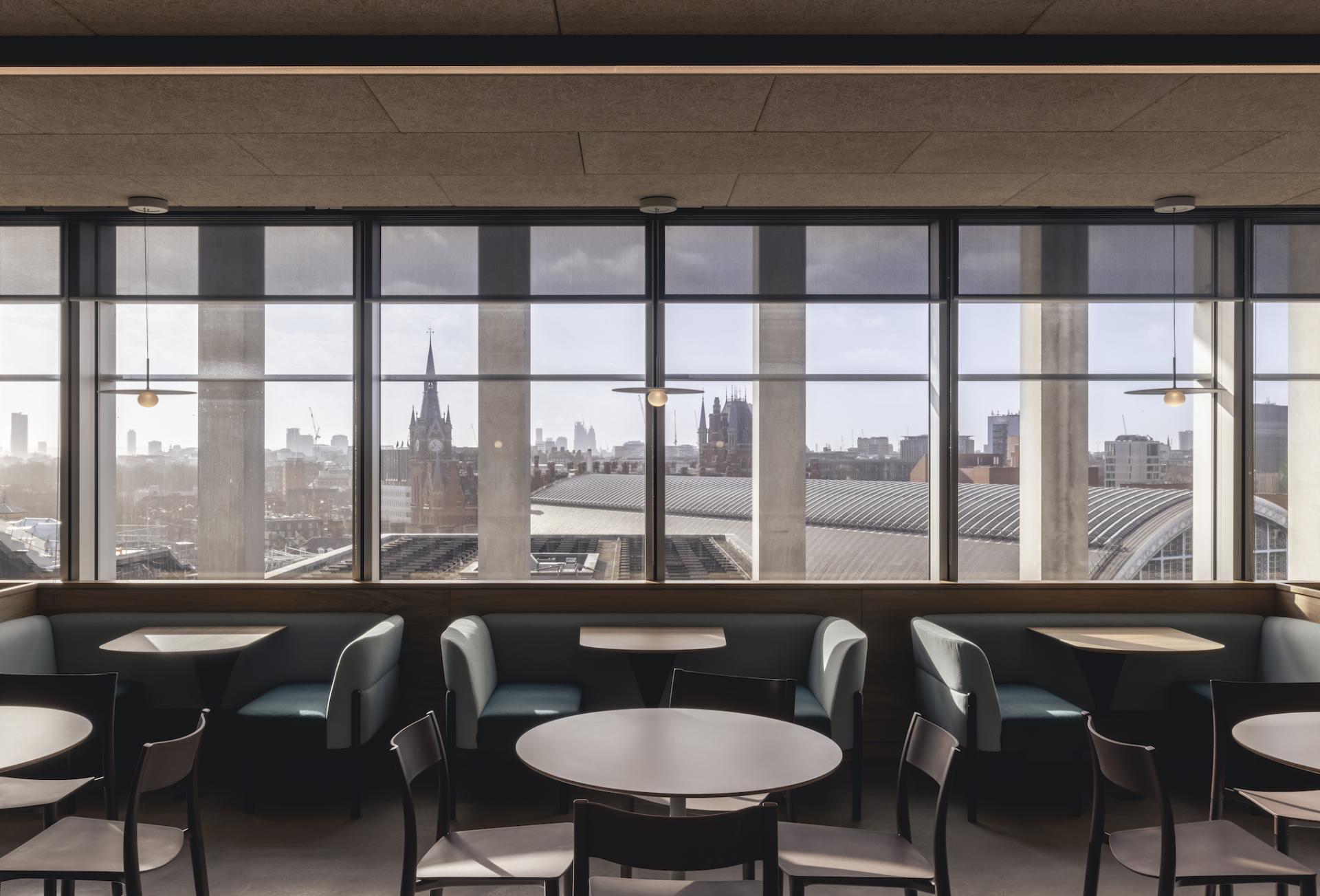 Modern workspace design at AstraZeneca UK features inviting seating and expansive windows showcasing a city skyline view.