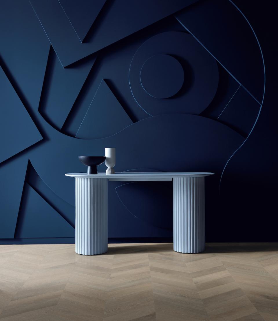 Stylish blue table with decorative items on a textured dark wall, showcasing Karndean's elegant rigid core flooring design.