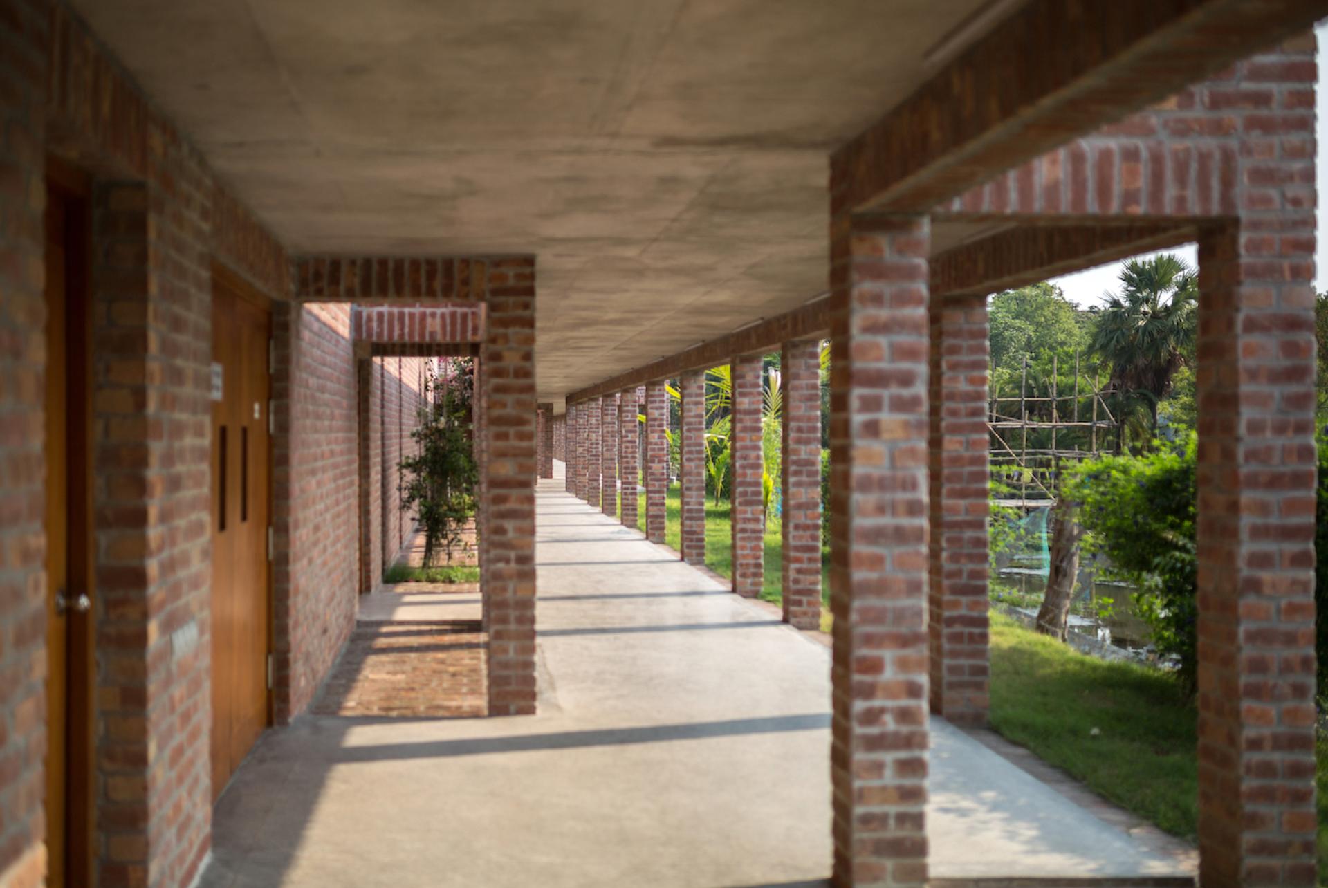 Contemporary brick corridor of Bangladesh hospital, showcasing sustainable architecture amidst lush greenery.