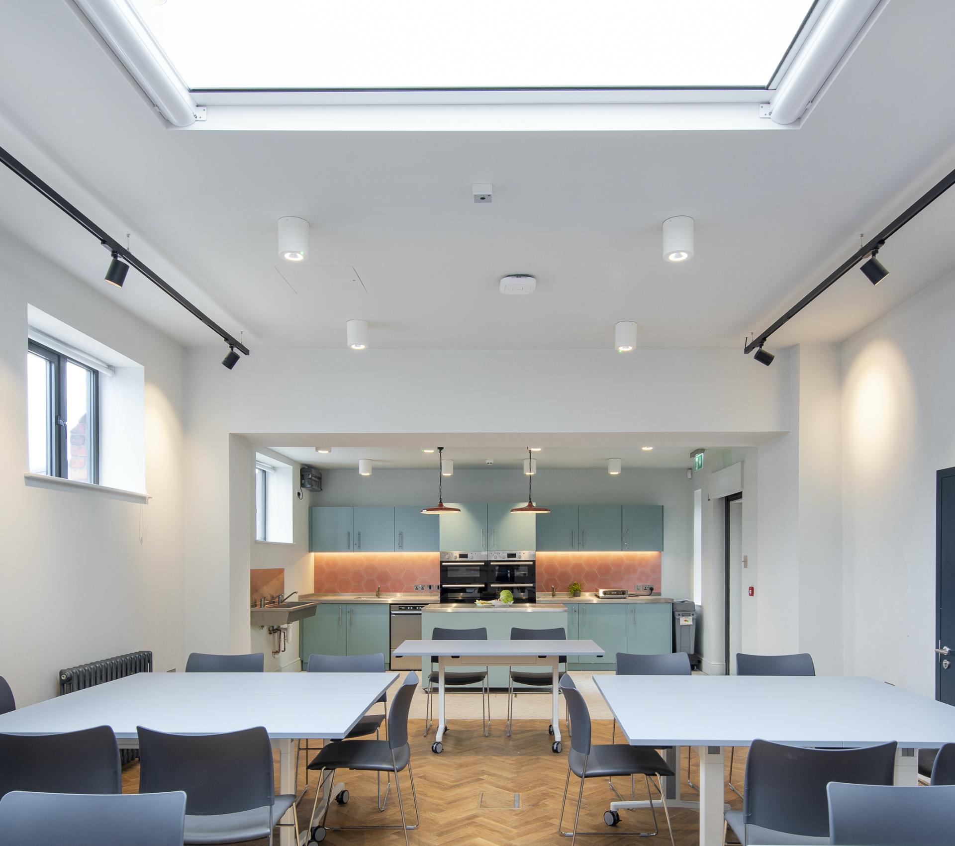 Modern kitchen area in Manchester Jewish Museum extension featuring industrial design elements and inviting communal dining space.