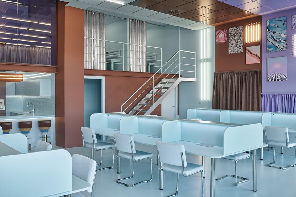 Modern coworking space in Valencia featuring colorful design, workstations, and a staircase, created by Masquespacio.