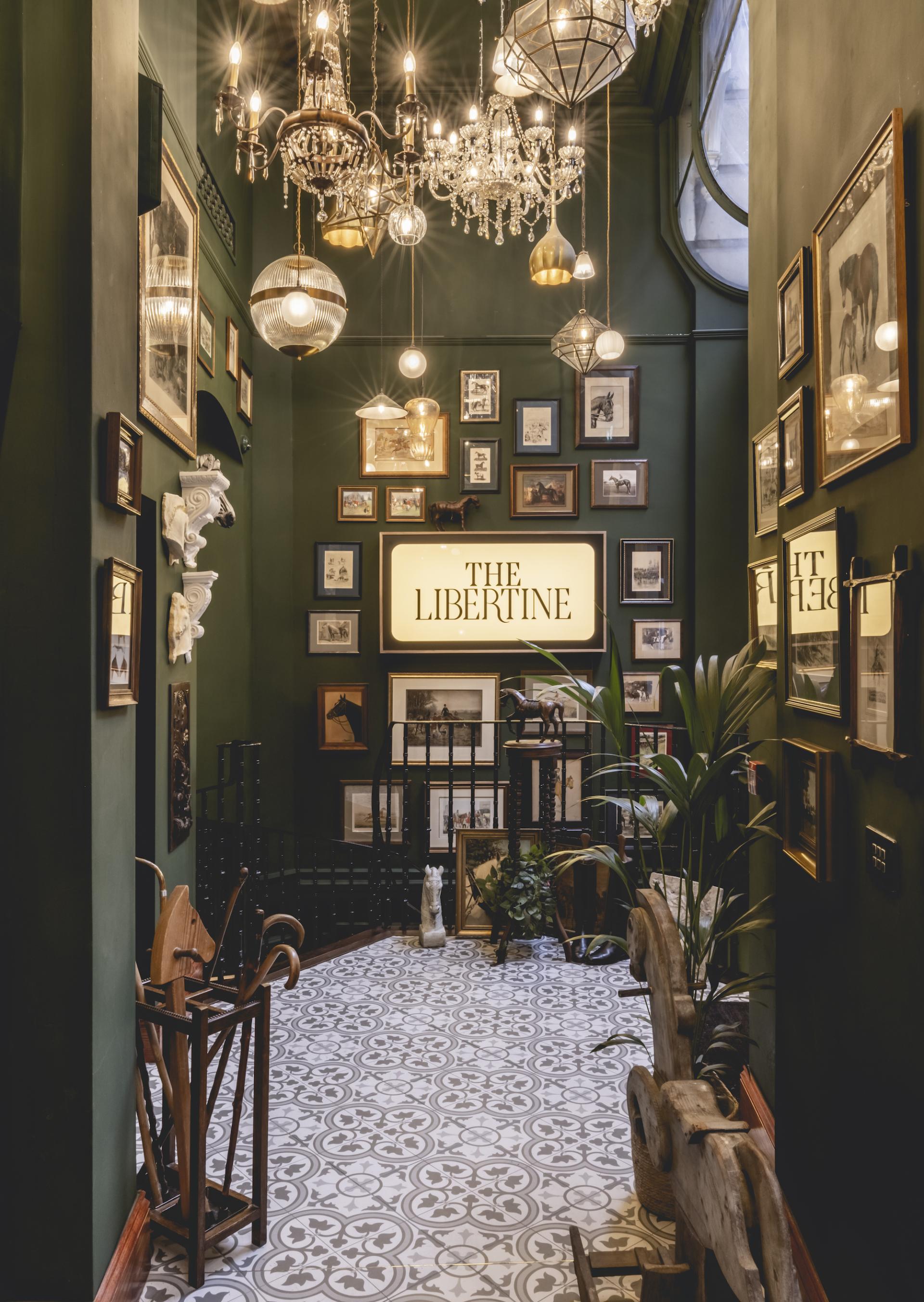 The entrance hallway of The Libertine, featuring stylish decor, vintage photographs, and intricate flooring in London's Royal Exchange.