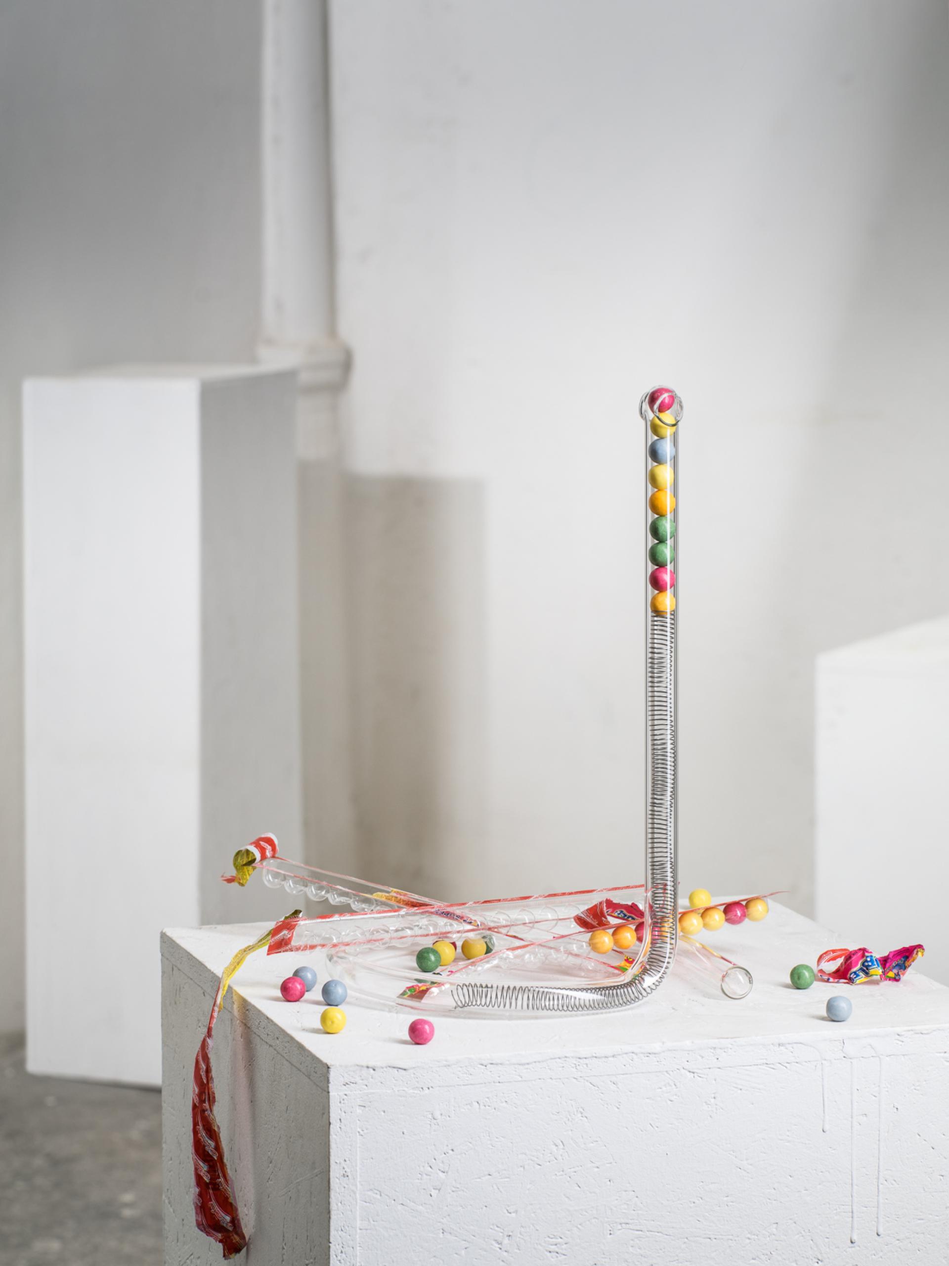 Artistic glass installation featuring colorful candy-like spheres, highlighting innovative use of transparency at the London Design Fair.