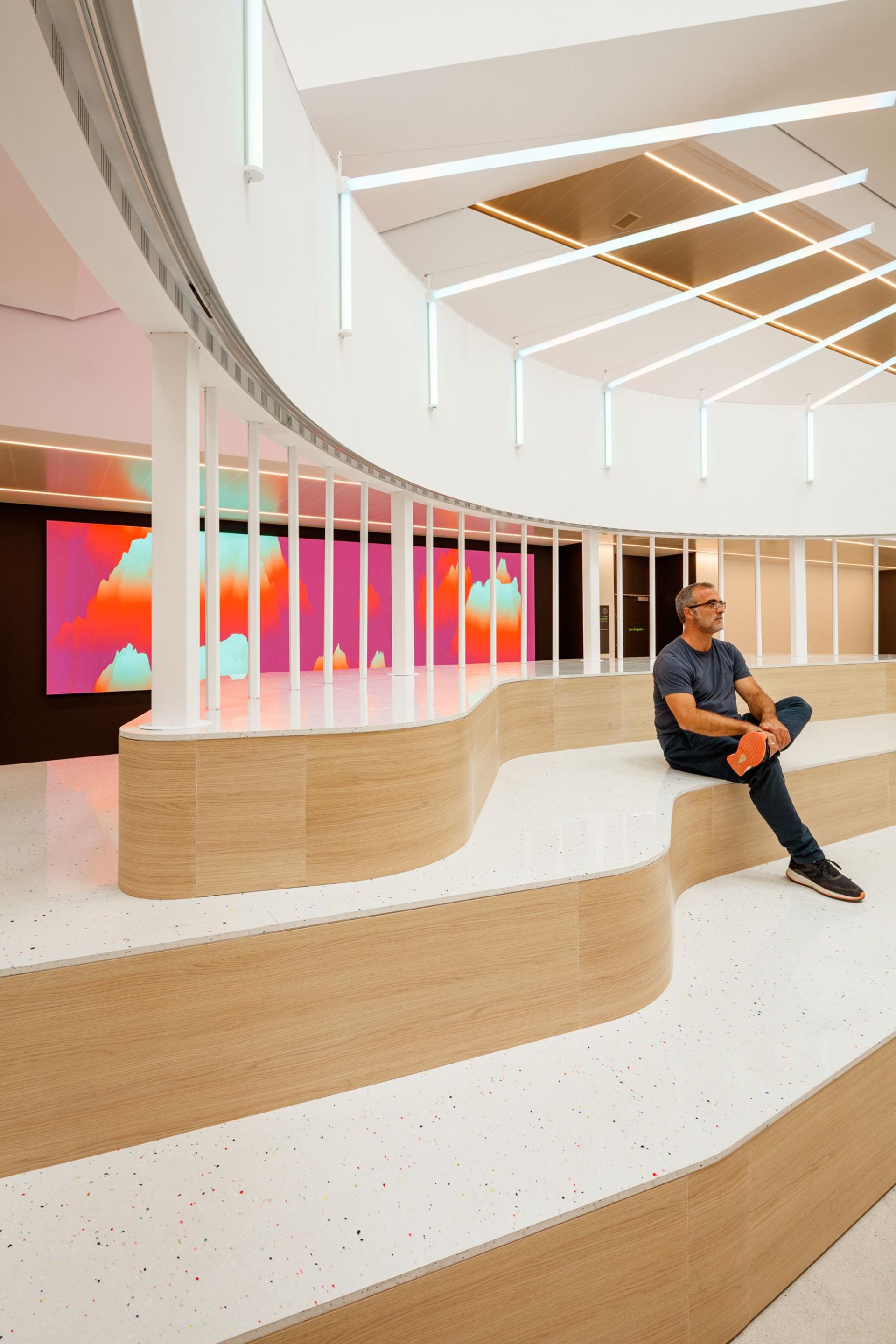 Modern interior featuring unique curved seating, showcasing solid surface materials and vibrant digital art backdrop.