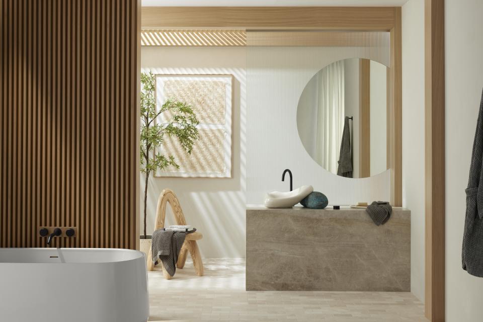 A modern bathroom featuring a limited-edition Kohler sink designed by Daniel Arsham, complemented by natural light and elegant decor.