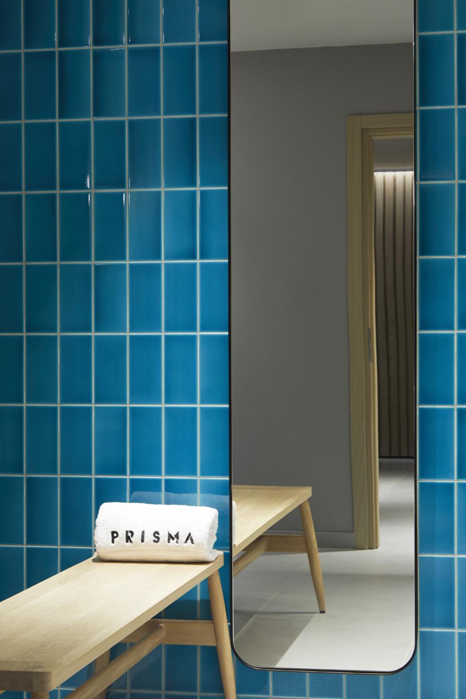 Bright blue tiled interior featuring a wooden bench with a towel, showcasing the stylish design of PURO Kraków Kazimierz.