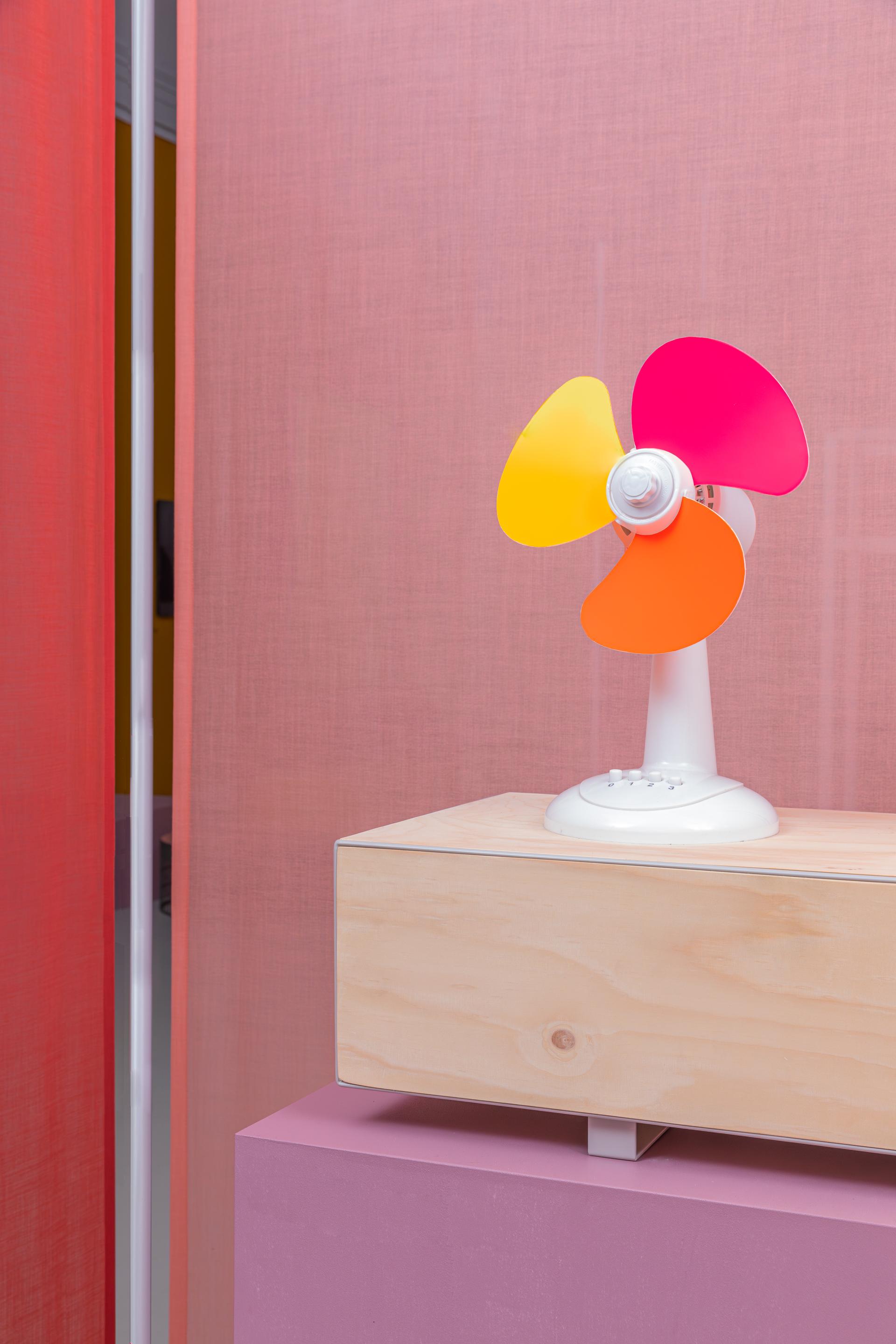 Colorful modern fan on a wooden table, reflecting Raw Color's innovative approach to materials and design.