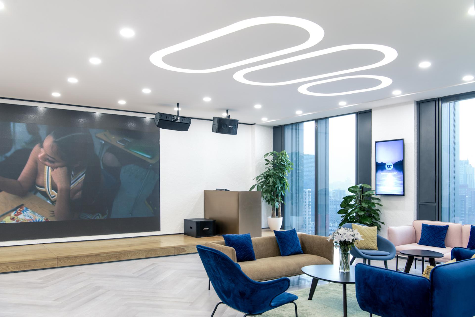 Innovative workspace designed by Bean Buro for Warner Music, featuring modern seating and large projection screens.