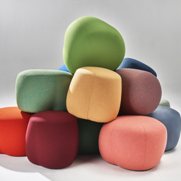 Colorful NaughtOne Truffle poufs stacked playfully, showcasing their modern design and versatility as seating or footrests.
