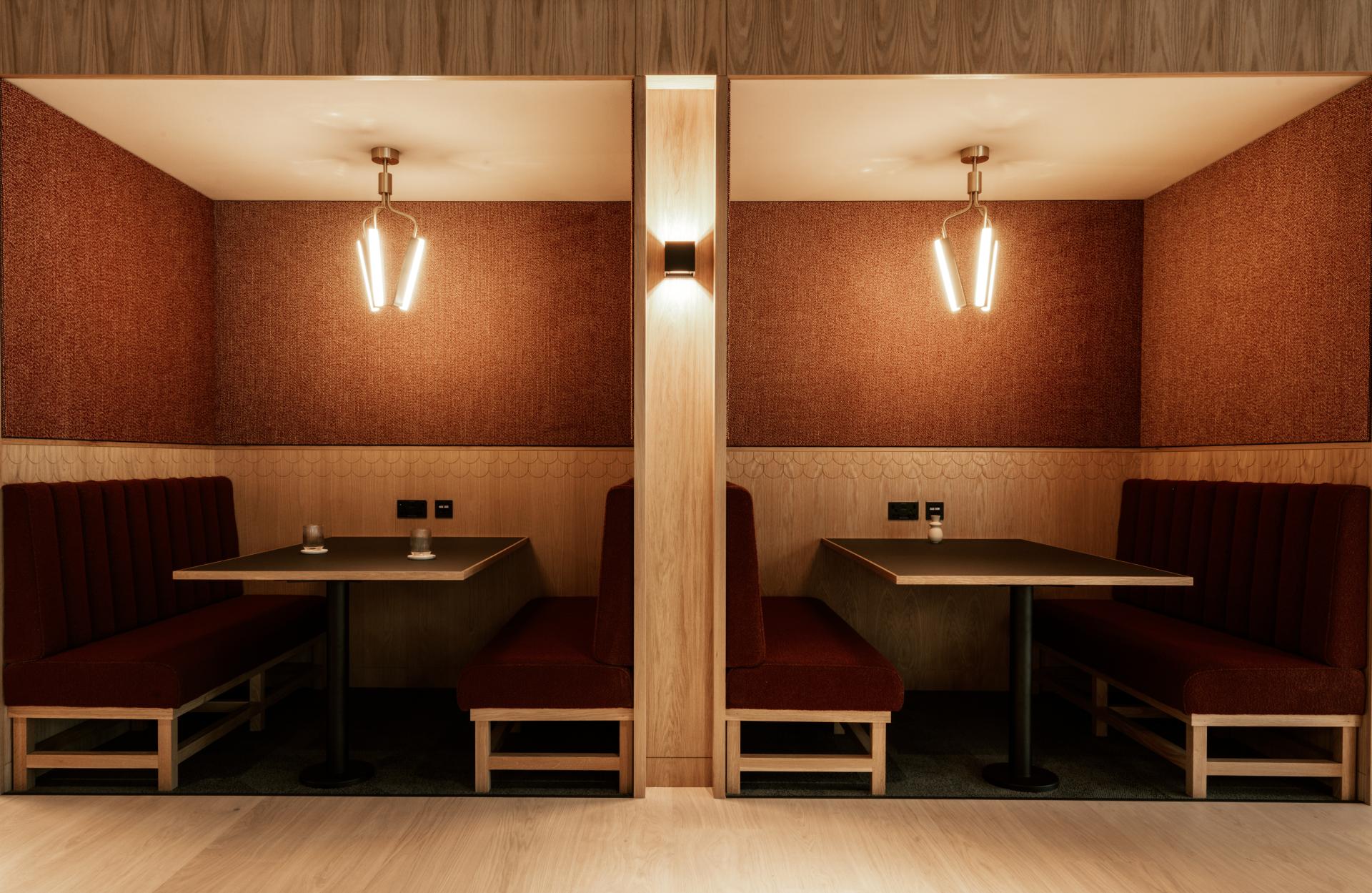Cozy seating booths with warm lighting in Dentons' Edinburgh workspace, showcasing modern design and makers heritage.