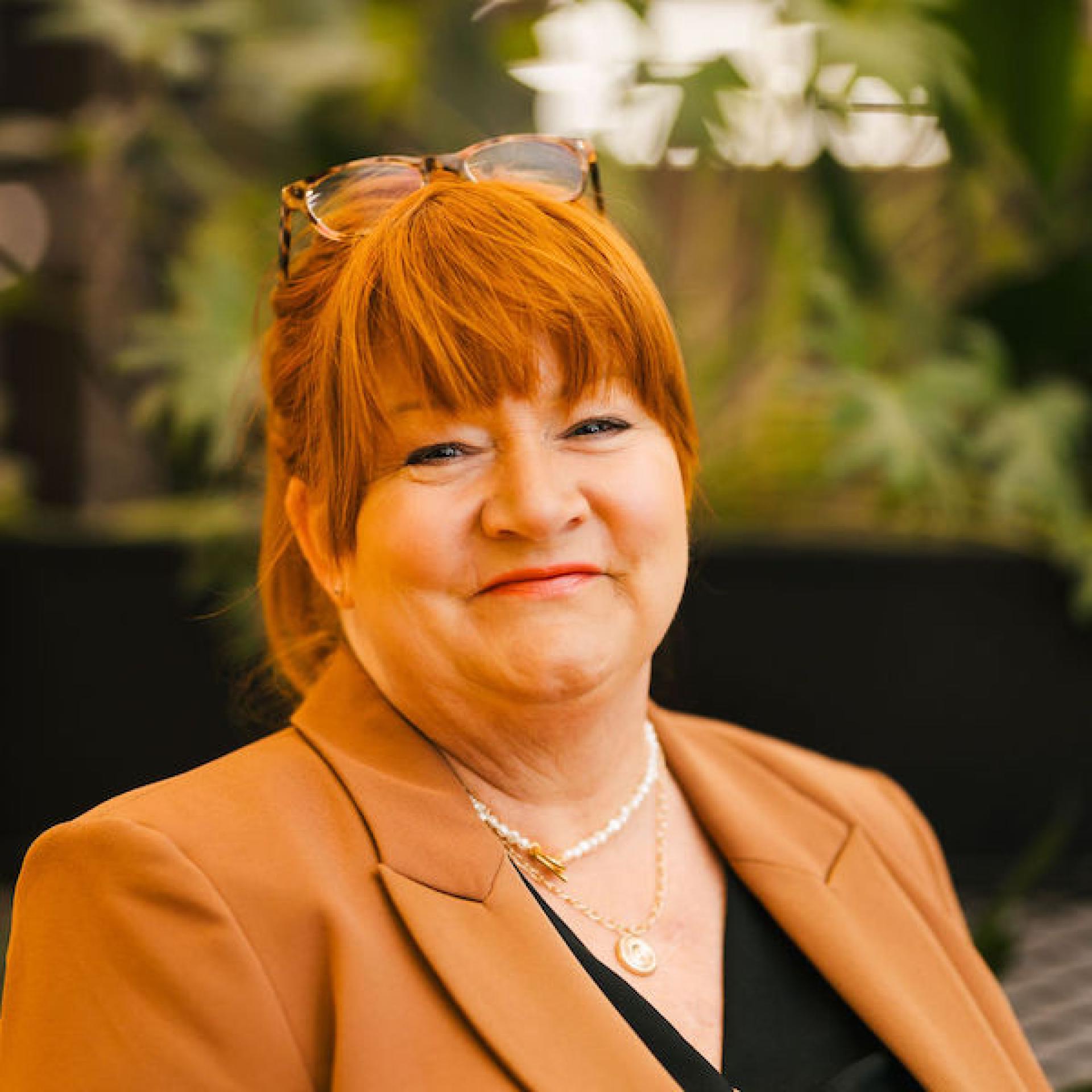 Professional woman in a blazer smiles warmly, representing Glasgow’s property discussions and future outlook.