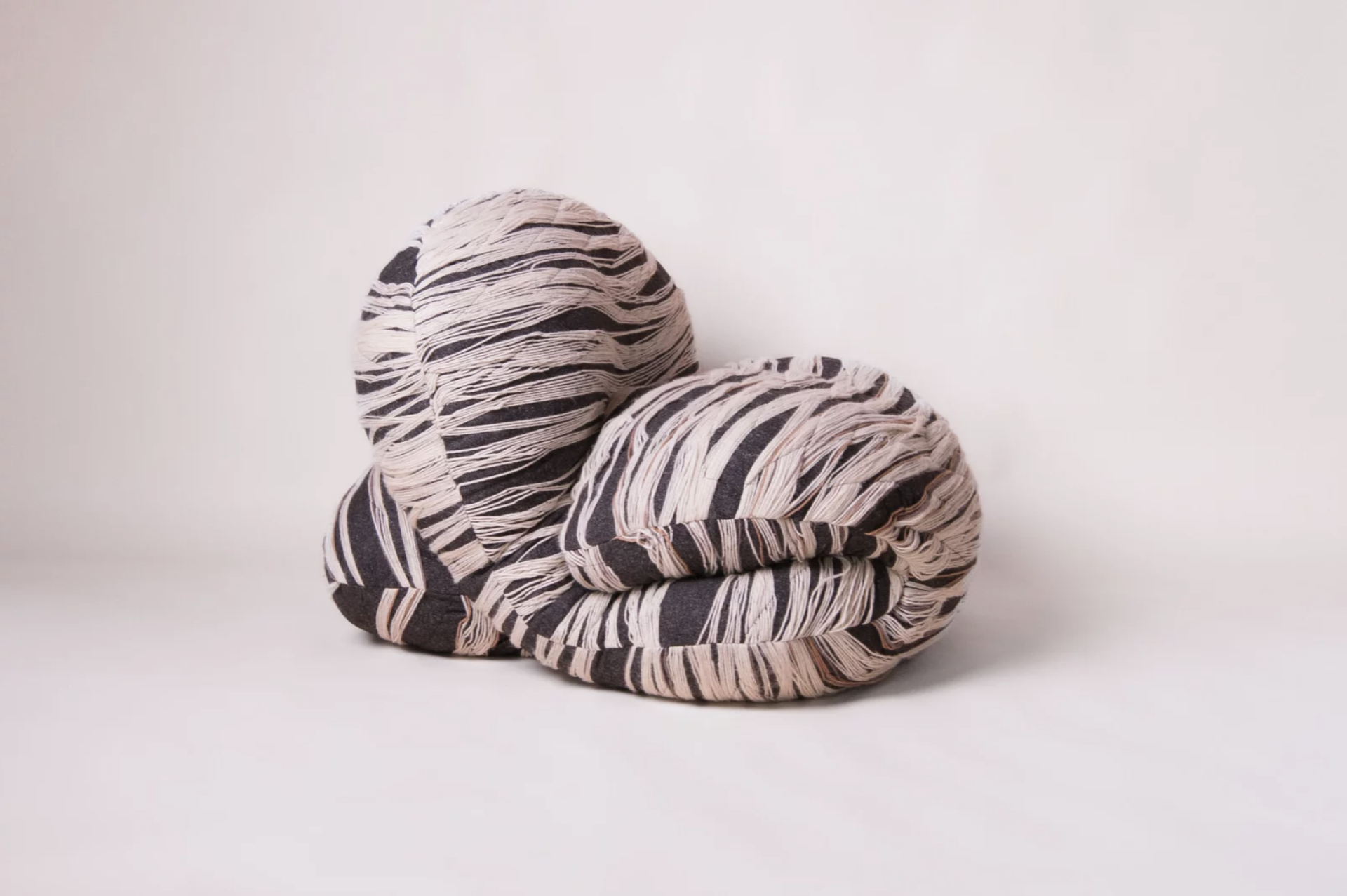 Textured, sustainable cushions in black and beige biomaterial, illustrating innovative design for low carbon products in 2025.