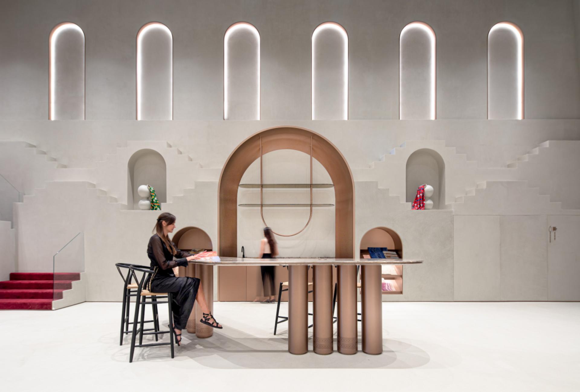 Modern interior design featuring a stylish workspace with unique architectural elements and a woman reviewing design materials.