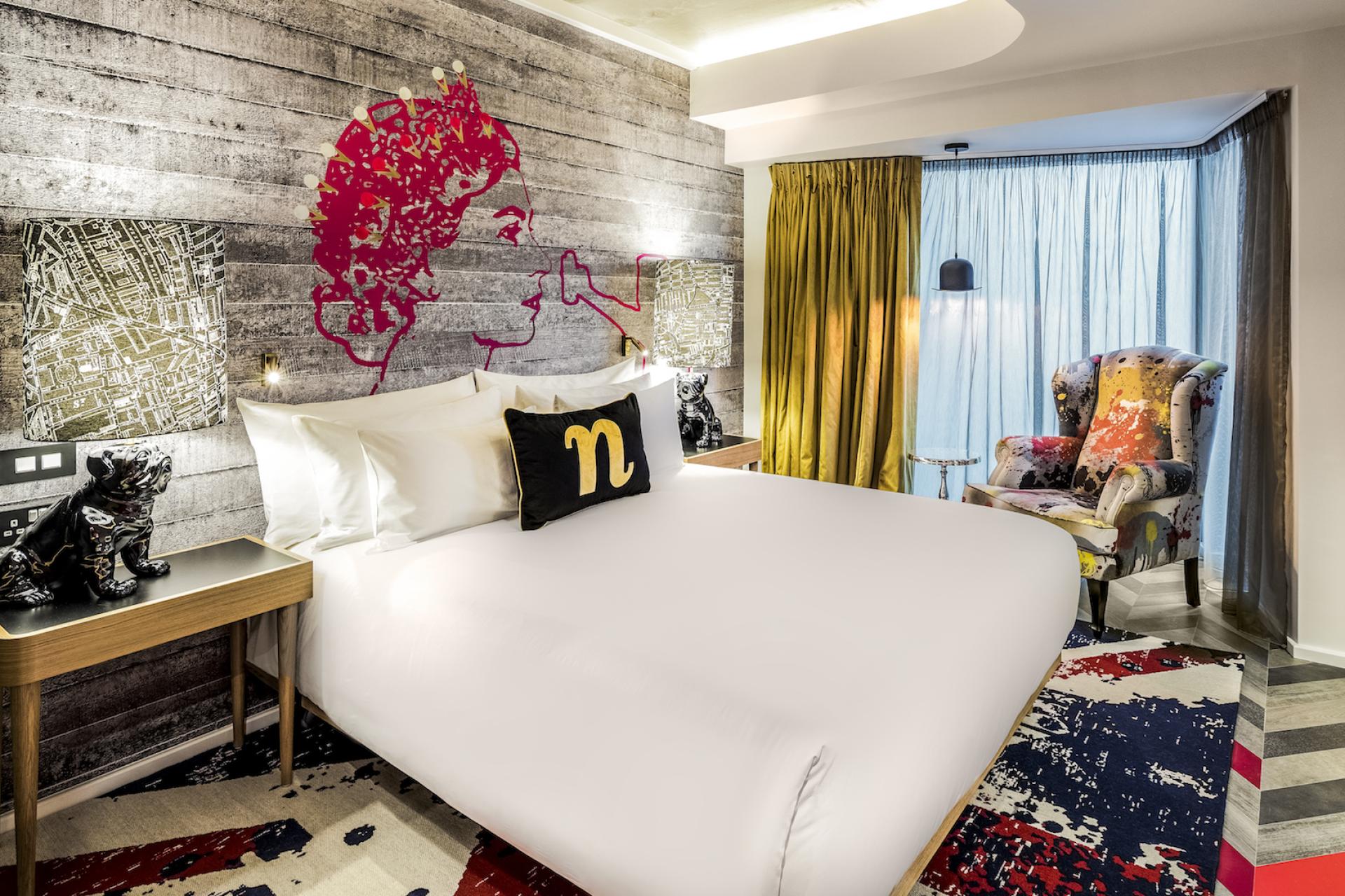 Stylish hotel room at nhow London featuring vibrant décor, a unique wall mural, and modern furnishings.
